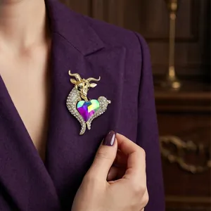 Elegant gold-toned goat brooch featuring a heart-shaped iridescent crystal on a blazer.