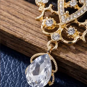Vintage palace style gold brooch with sparkling rhinestones and teardrop crystal pendant