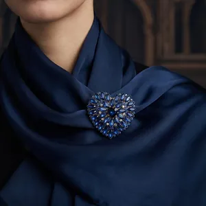 Luxury vintage heart-shaped brooch with vibrant blue crystals pinned on a silk scarf