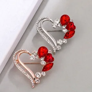 Elegant heart-shaped brooches with red crystals and white rhinestones on gray background