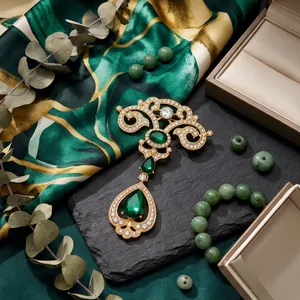 Vintage emerald teardrop brooch with gold filigree and pavé crystals on green silk