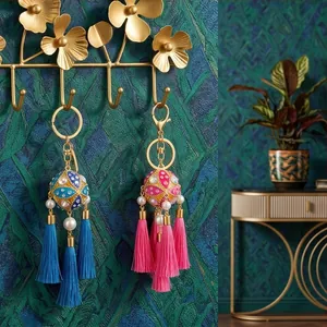 Detailed view of handmade ethnic embroidered ball tassels keychains on golden wall hooks