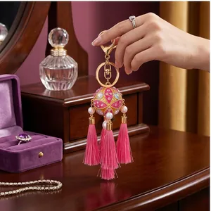 Detailed view of a traditional Chinese embroidered ball keychain with pink tassels.