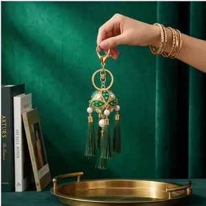Close-up detail of a traditional Chinese style embroidered ball keychain with green tassels