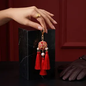 Close-up of a traditional Chinese red embroidered ball tassel keychain with gold finish