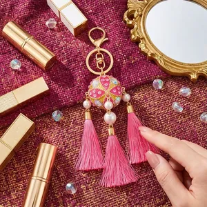 Handmade embroidered ball keychain with pink tassels and pearl accents, elegant bag charm.