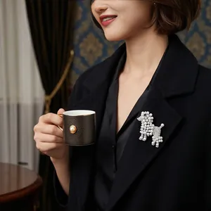 Broche élégante en forme de caniche avec perles et strass sur un blazer noir chic.