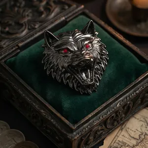 Vintage metallic wolf head brooch for men with red gemstone eyes on velvet cushion
