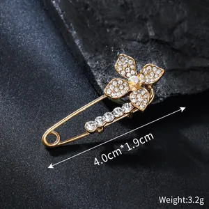 Macro view of a rhinestone flower safety pin brooch with clear size and weight markings.
