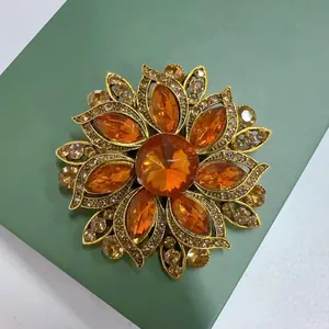 Makro-Detail einer Vintage-Blumenbrosche aus orangem Glas mit goldener Textur-Oberfläche