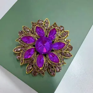Nahaufnahme einer Vintage-Brosche mit lila Kristallblumen und elegantem Goldton