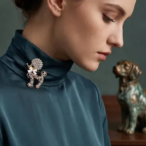 Élégante broche caniche avec strass étincelants épinglée sur un col de chemisier en soie verte.