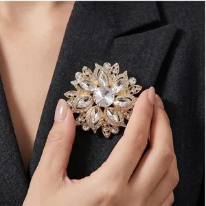 Klassische goldfarbene Blumenbrosche mit klaren Kristallen an einem dunklen Blazer
