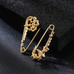 Detailed view of golden alloy safety pins with intricate floral patterns for cardigans.