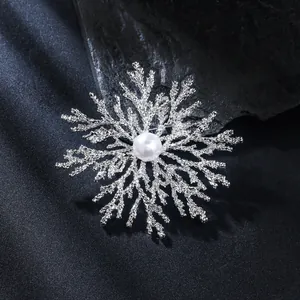 Macro detail of snowflake brooch featuring textured silver branches and central white pearl