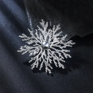 Detailed view of an elegant silver snowflake brooch with a grey pearl center piece