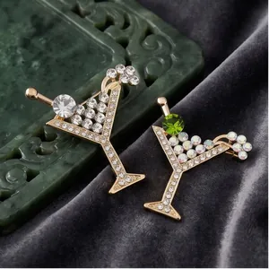 Elegantes broches de copa de cóctel con cristales brillantes sobre fondo terciopelo.