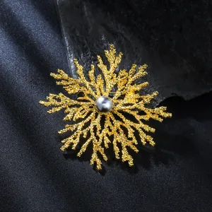 Close-up macro view of a luxury gold snowflake brooch featuring a dark grey pearl center