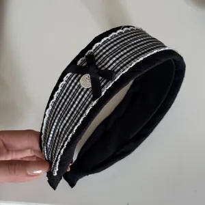 Close-up detail of a sweet black checkered lace headband featuring a cute bow and silver button.