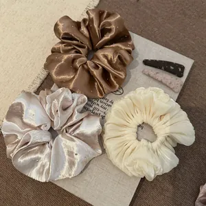Detailopname van satijnen scrunchies met strassteentjes en geplooide textuurdetails