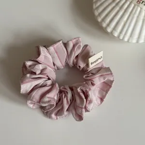 Detalle de un dulce coletero a rayas rosas de estilo coreano con etiqueta tela.