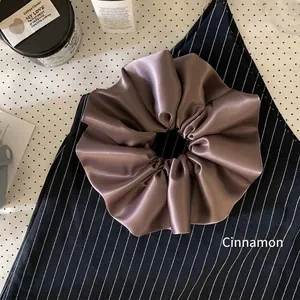 Close-up detail of a dark mauve oversized satin scrunchie with smooth silk texture