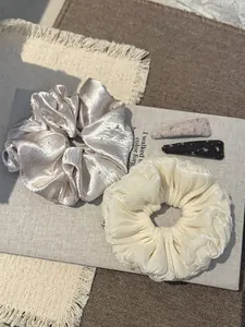 Detailopname van parelsatijnen scrunchies met strass en getextureerde haaraccessoires.