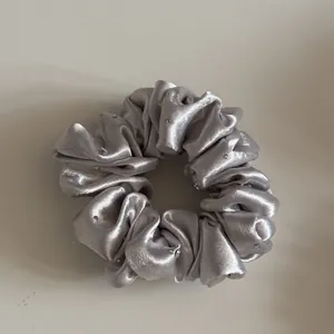 Gedetailleerd overzicht van een zilveren satijnen scrunchie met fijne strassteentjes.