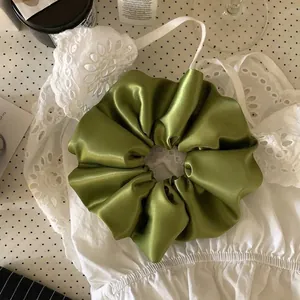 Premium mustard green satin scrunchie hair tie showing smooth texture and elegant folds