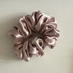 Detailweergave van champagnekleurige parelmoer satijnen scrunchie met strassteentjes