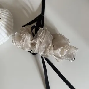 Close-up of a Korean style cream mesh bow hair clip with elegant black ribbon accents