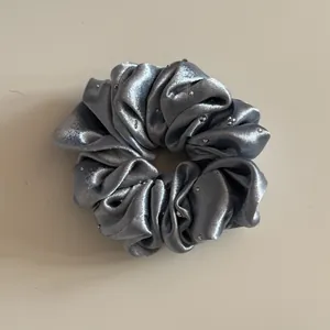 Detailweergave van zilveren parelmoer satijnen scrunchie met strass stersteentjes