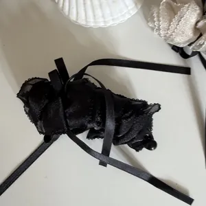 Detailed view of black ruffled mesh banana hair clip featuring elegant long satin ribbons