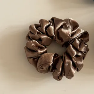 Close-up van een bruine satijnen scrunchie met glanzende en elegante strass-steentjes
