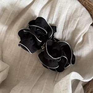 Detailed view of the black and white ruffled mesh bow hair clip with pearl accents.
