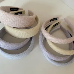 Detail view of cream pastel colored textured fabric headbands with handmade labels