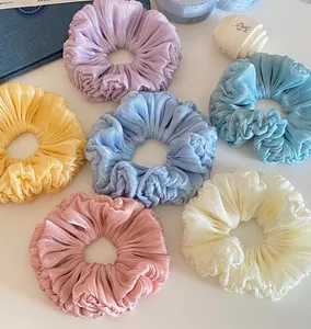 Detail view of multi-colored pleated scrunchies featuring a soft shimmer and crinkled fabric
