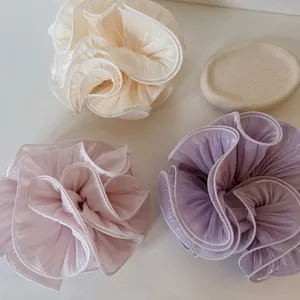 Detail shot of three pearlescent oversized satin scrunchies in soft pastel shades