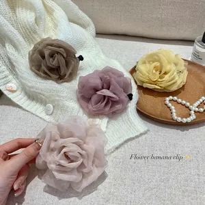 Detail of elegant chiffon flower banana clips in multiple soft colors on fabrics