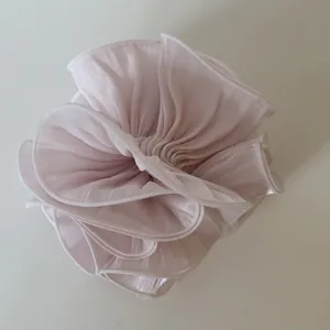 Macro detail of a large pearly satin scrunchie with elegant pleated flower design