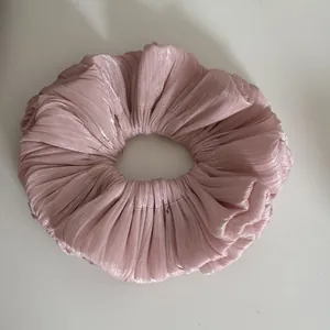 Close-up of shimmering pleated pink scrunchie with a soft metallic texture