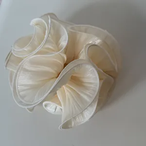 Detailed view showing the shimmering texture of an oversized pleated cream satin scrunchie