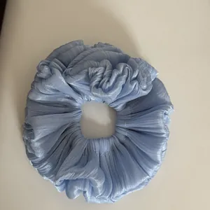 Detailed view of light blue shimmering pleated fabric scrunchie with soft texture