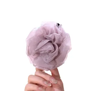 Detailed view of a large dusty purple chiffon flower hair clip held against white background.