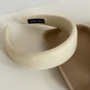 Close-up of a cream-colored wide fabric headband with textured finish and handmade tag