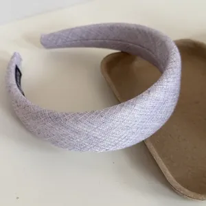 Detail view of a wide lavender padded headband with textured fabric and hand-made tag.