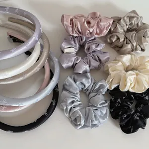 Detailed view of satin scrunchies and headbands featuring a delicate white bow pattern