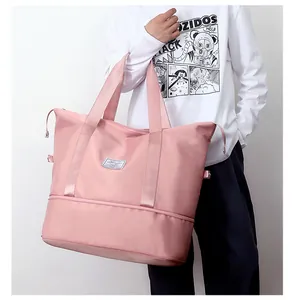 Detailed view of large pink expandable travel bag held by person against a white wall