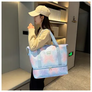 Detailed view of an expandable quilted travel bag in blue and pink gradient carried by a model.