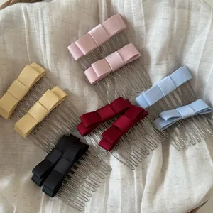 Selection of colorful satin bow hair combs displayed on soft textured fabric background.